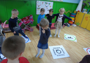 Dzieci wykonują ćwiczenia gimnastyczne według instrukcji obrazkowej